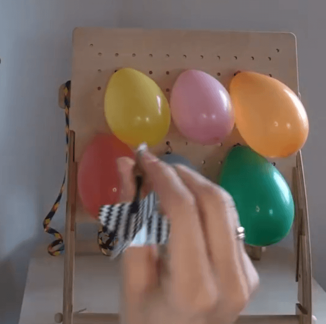 Binde Luftballons an der Lochplatte fest und spicker sie