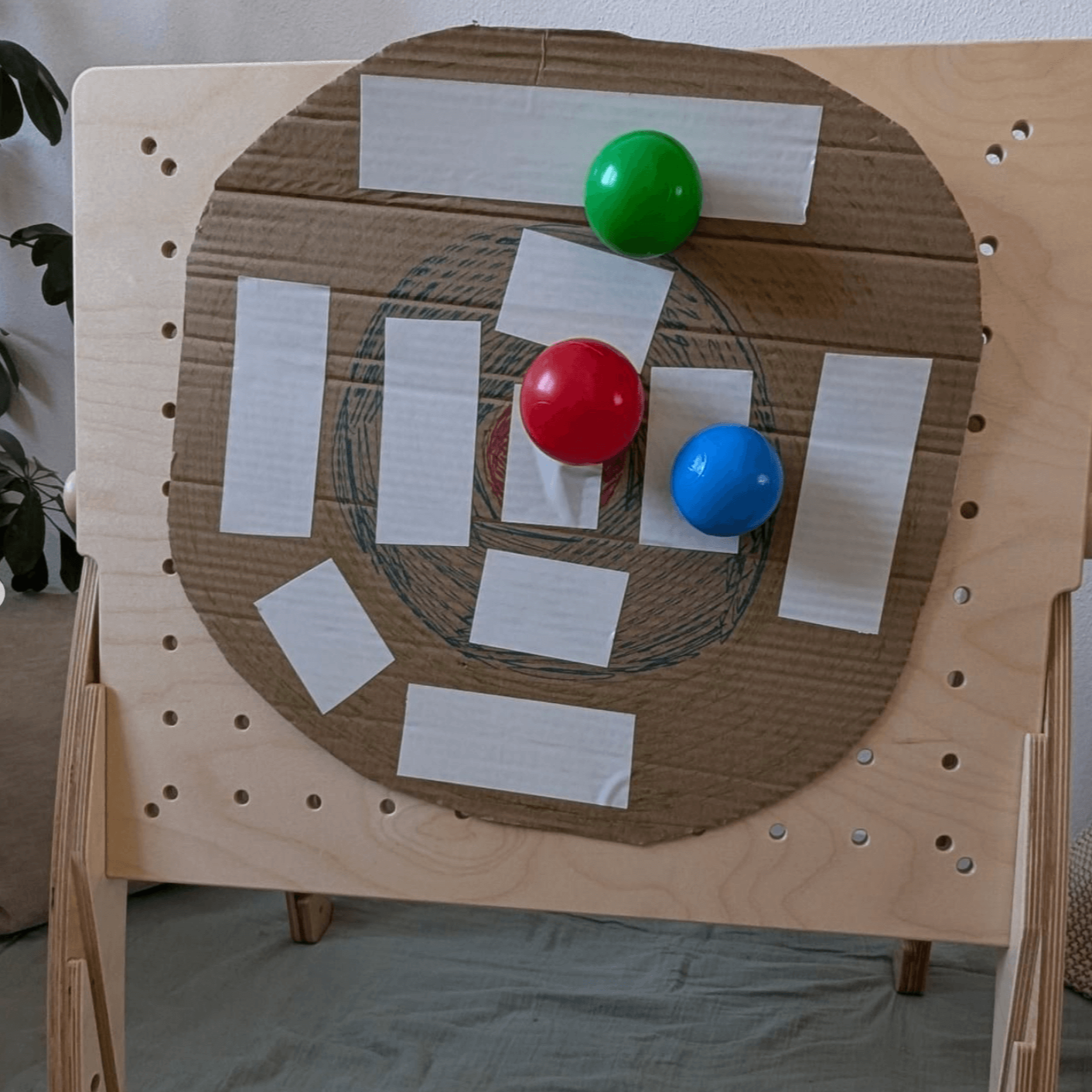Befestige eine selbstgebastelte Wurfplatte aus Karton auf der Lochplatte und über werfen