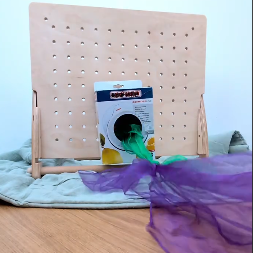 Befestige einen Karton mit Tüchern an der Lochplatte. Dein Kind hat Spaß die Tücher herauszuziehen